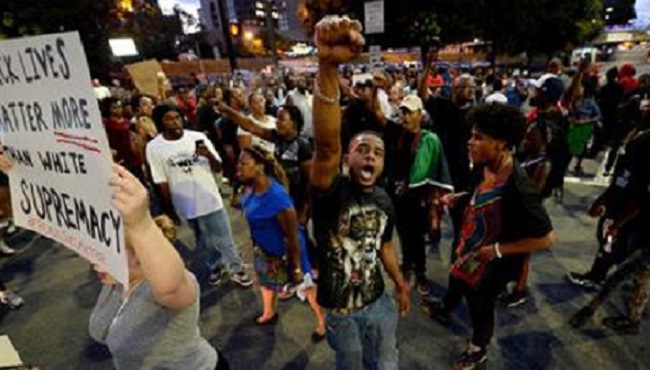 Protesters block an intersection near the Transit Center as they march uptown in Charlotte N.C. Wednesday Sept. 21 2016. Authorities in Charlotte tried to quell public anger Wednesday after a police officer shot a black man but a dusk prayer vigil tur