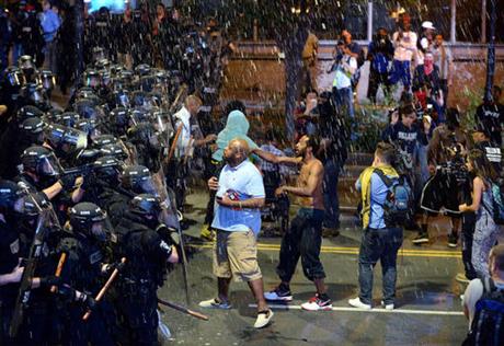 Debris falls upon Charlotte Mecklenburg police officers and protesters as officers began to push protesters from the intersection near the Epicentre in Charlotte N.C. Wednesday Sept. 21 2016. Authorities in Charlotte tried to quell public anger Wednesd