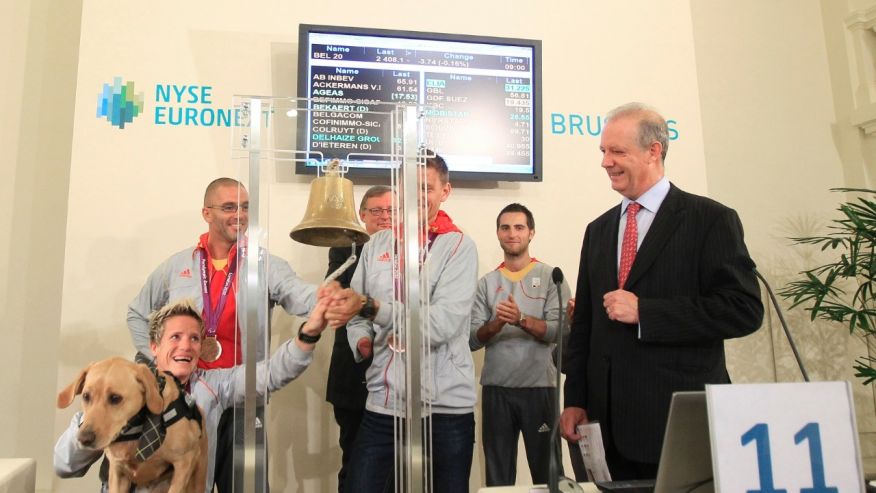 Belgian athlete Marieke Vervoort rings a bell in the presence of fellow athletes Wim Decleir and Frederic Van den Heede, NYSE Euronext Brussels CEO Vincent Van Dessel and her dog Zenn after their return from the London 2012 Paralympi