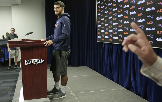 New England Patriots Jimmy Garoppolo left faces reporters as a member of the Patriots media relations staff hand only at right signals to reporters the