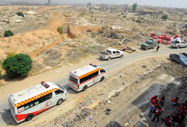 A Syrian Arab Red Crescent convoy waits at the entrance of the besieged Damascus suburb of Daraya