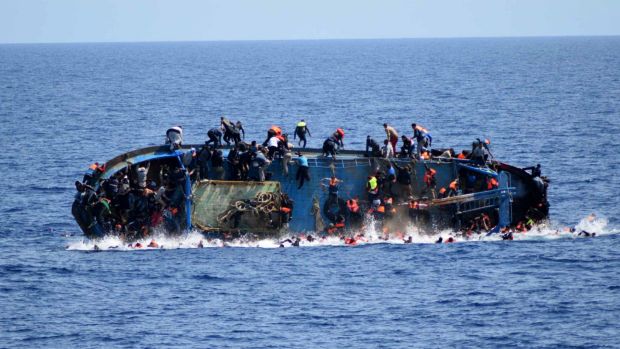 People jump off a boat moments before it overturns off the Libyan coast in May