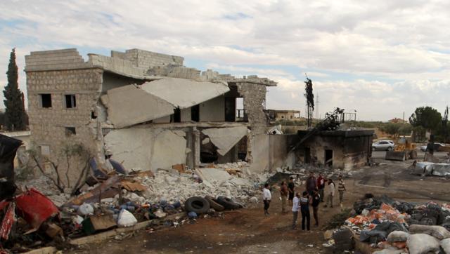 People stand near damaged aid supplies after an airstrike on Tuesday on the rebel held Urem al Kubra town