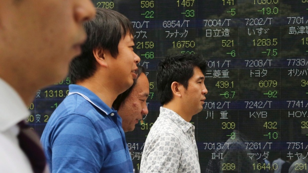 People walk by an electronic stock board of a securities firm in Tokyo