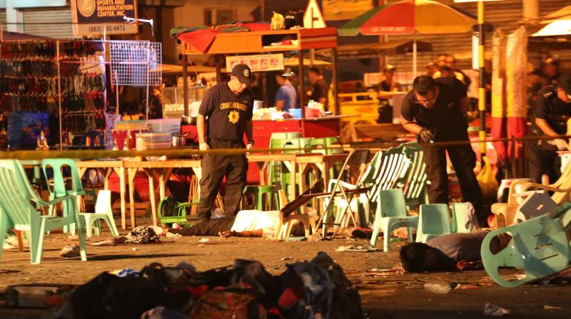 Philippine police officers look at dead victims after an explosion at a night market that has left about 10 people dead and wounded several others in southern Davao city