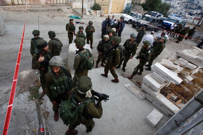 Israeli security forces gather at the scene of a stabbing attack against an Israeli soldier in Hebron West Bank