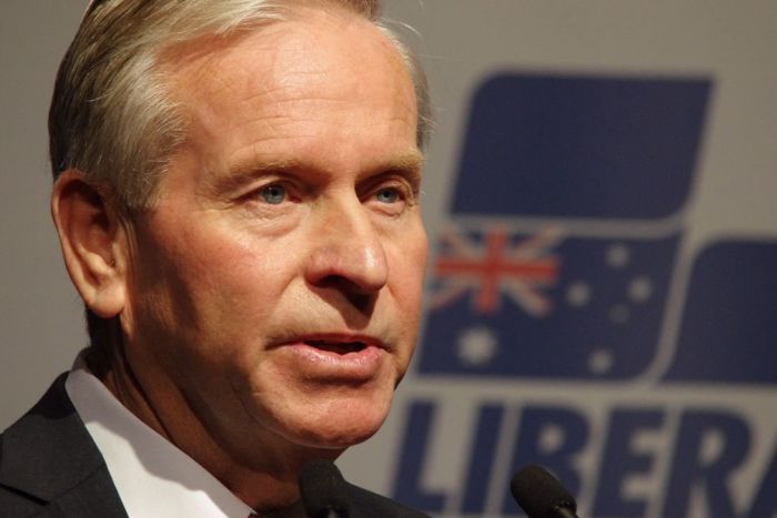 Head shot of WA Premier Colin Barnett in front of a Liberal Party sign