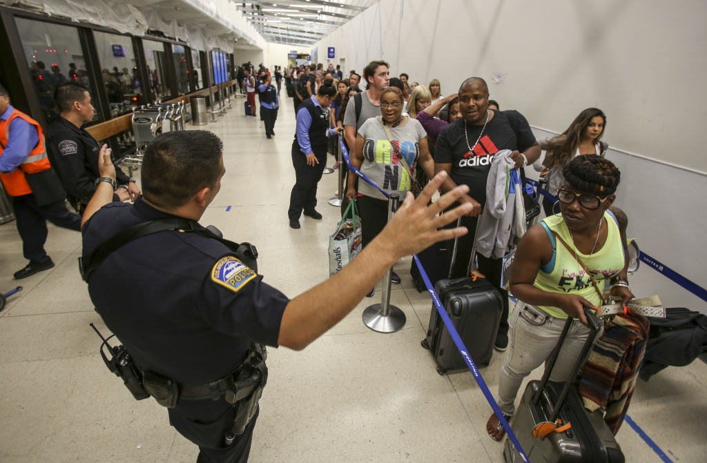 Police officers stand guard as passengers wait in line at Terminal 7 in Los Angeles International Airport