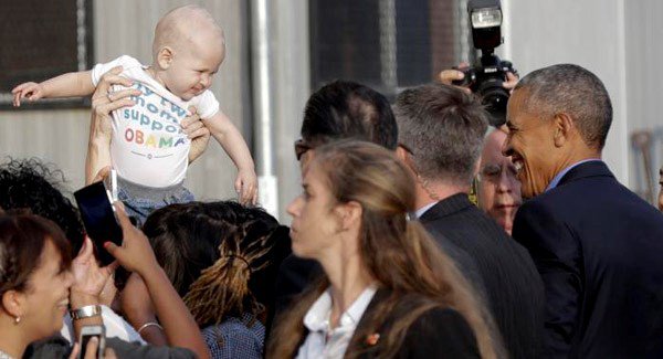 President Barack Obama smiles at a baby as he greets people at John F. Kennedy International Airport in New York