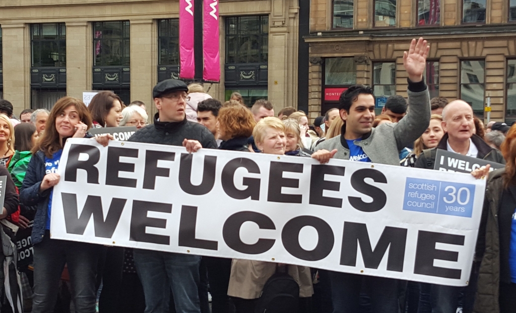 Members of the Scottish public carry a banner supporting the effort to accommodate refugees