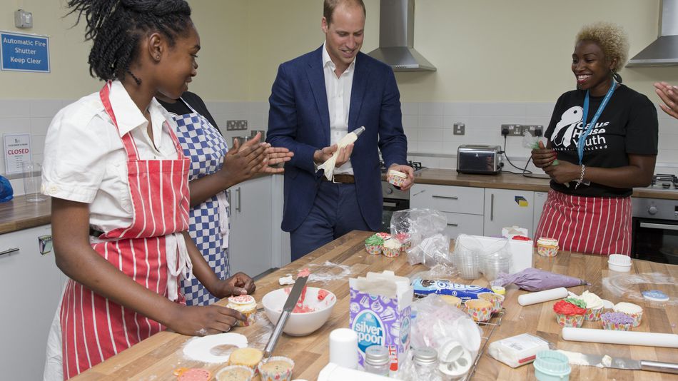 Prince William Duke of Cambridge ices a cake as he takes part in a baking class with young people and volunteers during a visit to Caius House Youth Centre