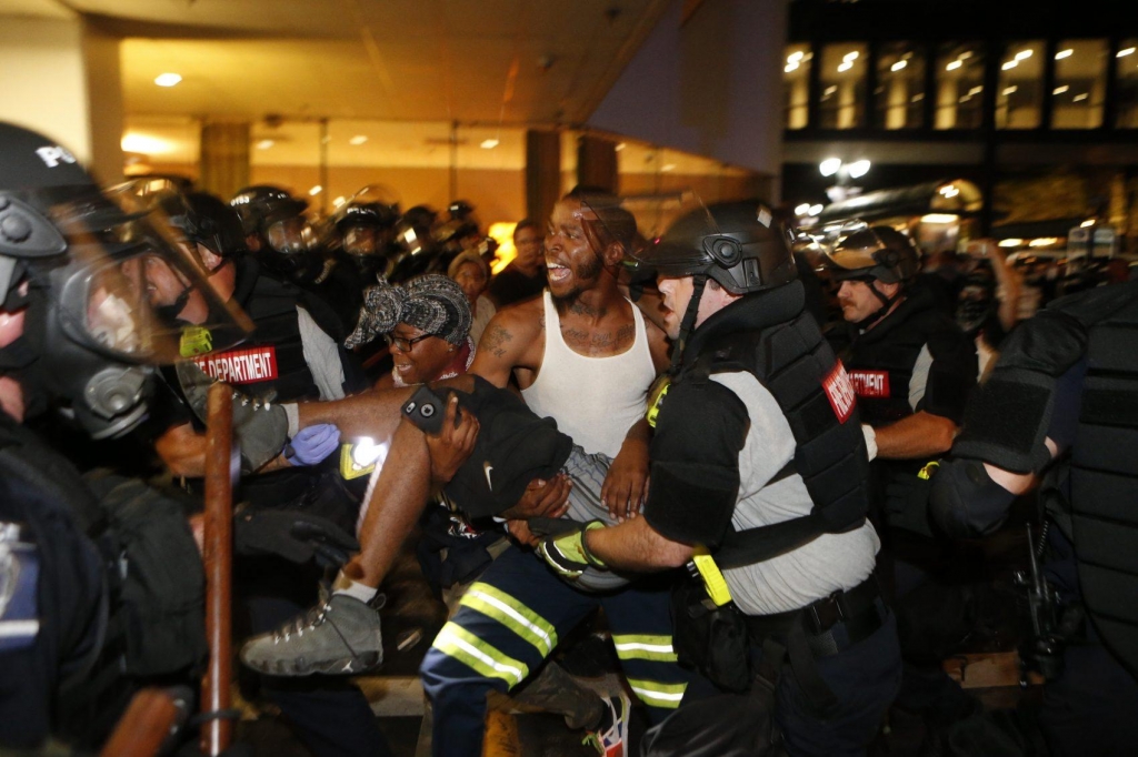 Police and protesters carry a seriously wounded protester into the parking area of the the Omni Hotel during a march to protest the death of Keith Scott Sept. 21 2016 in Charlotte N.C