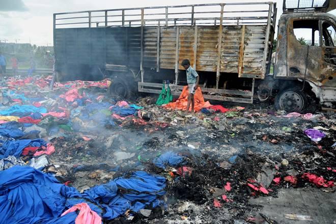 Bengaluru: People collect valuable remains from a Tamil Nadu Goods truck that was set on fire by the protesters during protests over Cauvery issue at Nice Road in Bengaluru on Tuesday. PTI