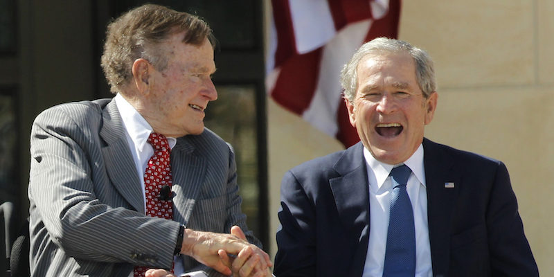 Father and son and former U.S. Presidents George H.W. Bush and George W. Bush shake hands at the dedication for the George W. Bush Presidential Center on the campus of Southern Methodist University in Dallas Texas