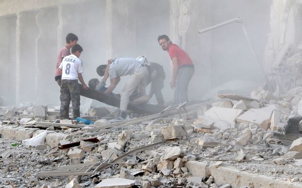 Rescue workers move an injured man from the rubble after airstrike in the Al Ansari district of Aleppo