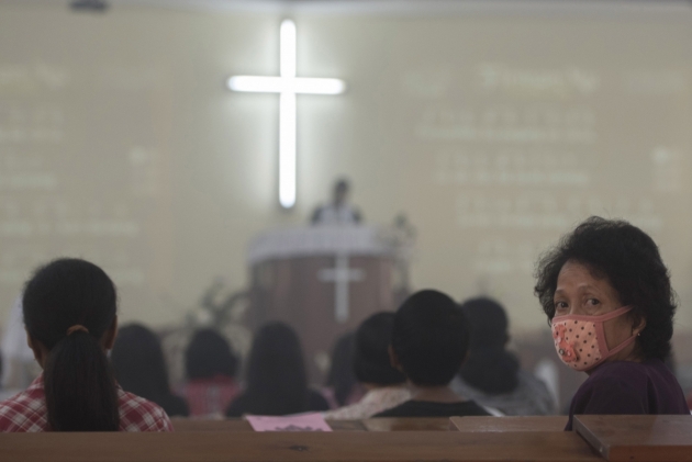 A woman wearing a mask attends a Sunday Mass prayer session at Sion Church in Palangkaraya Indonesia