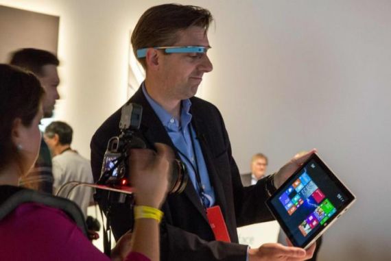 An event attendee in New York wears a Google glass while using the Microsoft Surface Pro 3 detachable