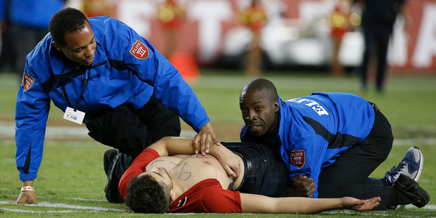 A fan is tackled by security officers during the second half of an NFL football game between the San Francisco 49ers and the Los Angeles Rams