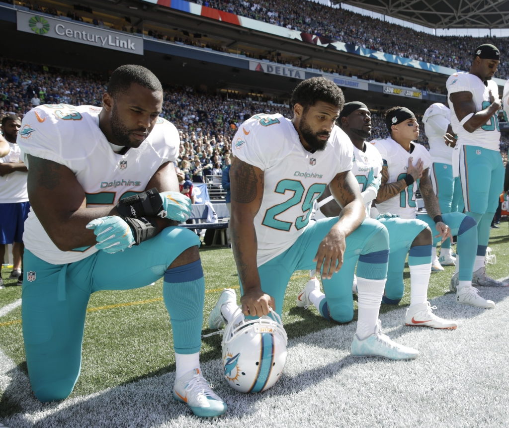 From left Miami Dolphins Jelani Jenkins Arian Foster Michael Thomas and Kenny Stills kneel during the singing of the national anthem before an NFL football game against the Seattle Seahawks Sunday Sept. 11 2016 in Seattle. (AP