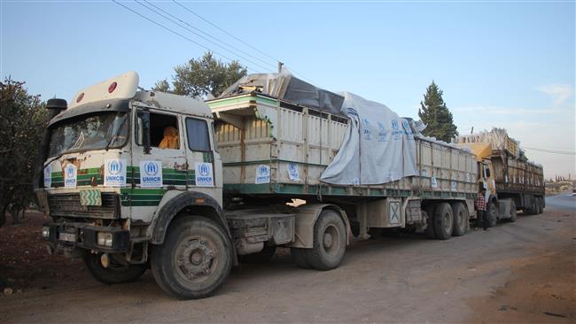 Trucks carrying aid are seen on the side of the road in the town of Orum al Kubra on the western outskirts of the northern Syrian city of Aleppo