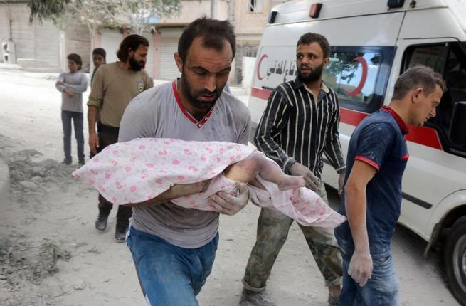 A Syrian man carries the body of an infant retrieved from under the rubble of a building following a reported airstrike