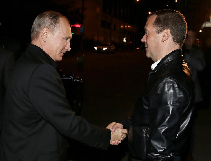 Russian President Vladimir Putin greets Prime Minister and Chairman of the United Russia party Dmitry Medvedev during a visit to the party's campaign headquarters following a parliamentary election in Moscow