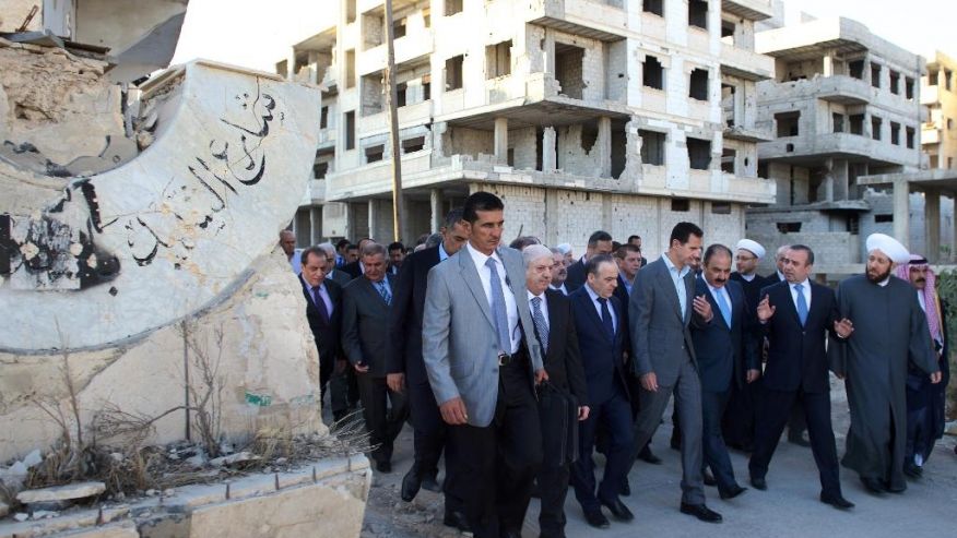 Syrian official news agency SANA Syrian President Bashar Assad center walks on a street with officials after performing the morning Eid al Adha prayers in Daraya a blockaded Damascus suburb Syria Monday Sept. 12 2016