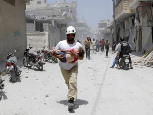 A civil defence member carries an injured girl at a site hit by airstrikes in the rebel-controlled area of Maaret al Numan town in Idlib province Syria