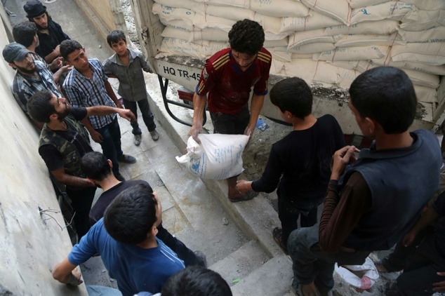 Syrians offload aid after a convoy of Syrian Arab Red Crescent and UN vehicles arrived in a rebel-held area on the outskirts of Damascus