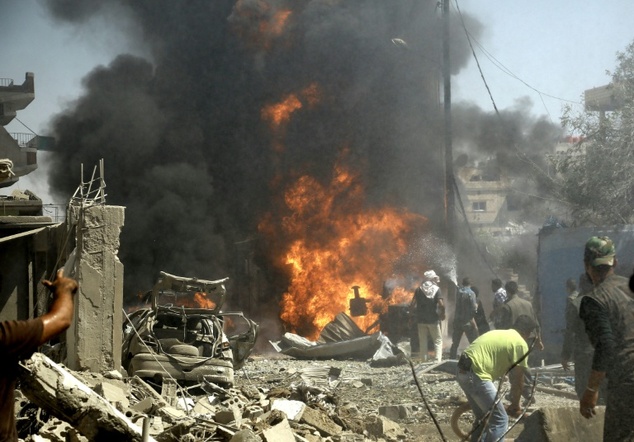 Residents gather at the site of a bomb attack in Syria's northeastern city of Qamishli