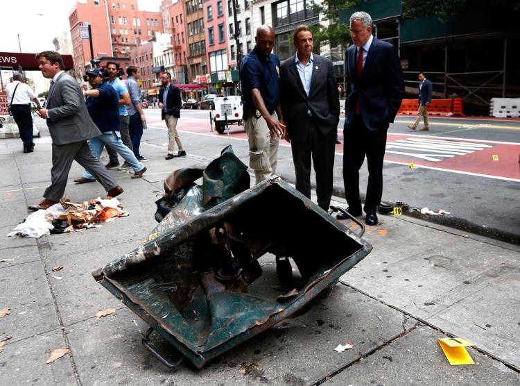 New York City Mayor de Blasio and New York Gov. Cuomo look over a mangled dumpster while touring the site of the Chelsea blast