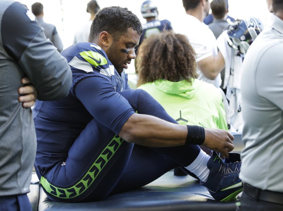 Seattle Seahawks quarterback Russell Wilson laces his shoe after getting his ankle taped following a play during the second half of an NFL football game against the Miami Dolphins Sunday Sept. 11 2016 in Seattle