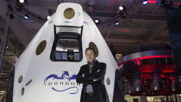 SpaceX CEO Elon Musk poses by the Dragon V2 spacecraft in Hawthorne