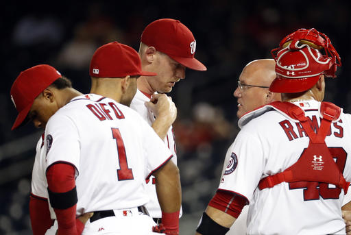 CORRECTS DIFO'S POSITION TO THIRD BASEMAN NOT SHORTSTOP- Washington Nationals third baseman Wilmer Difo left and shortstop Danny Espinosa stand as starting pitcher Stephen Strasburg talks with trainer Paul Lessard with