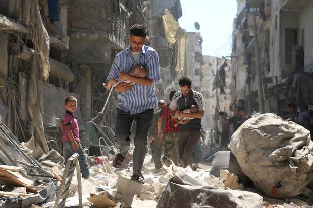 Syrian men carrying babies make their way through the rubble of destroyed buildings following a reported air strike on the rebel-held Salihin neighbourhood of the northern city of Aleppo on Sept. 11 2016