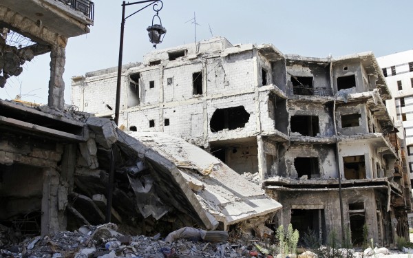 Damaged buildings and rubble line a street in Homs