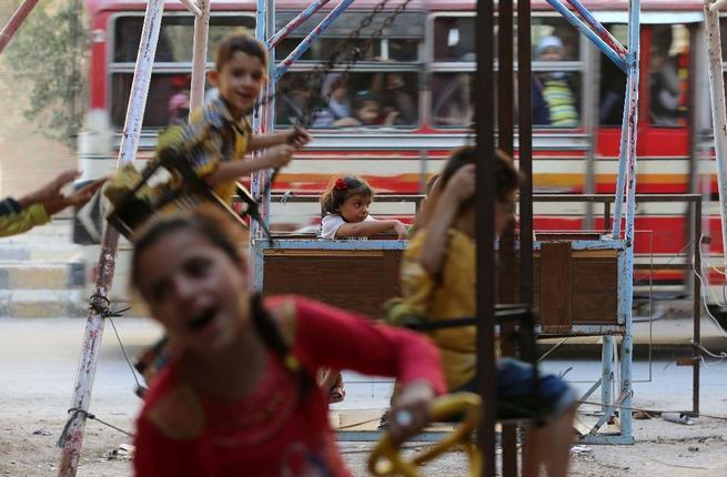 Syrian children play on swings in Arbin on the outskirts of the capital Damascus as they celebrate the Muslim Eid al Adha holiday