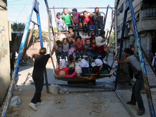 Syrian children ride an attraction in the Syrian rebel-held town of Arbin in the eastern Ghouta region on the outskirts of the capital Damascus as they celebrate the Muslim Eid al Adha holiday