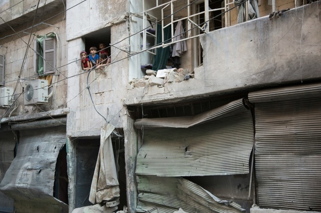 Syrian children look at the damage following an air strike in Aleppo's rebel-controlled neighbourhood of Karm al Jabal