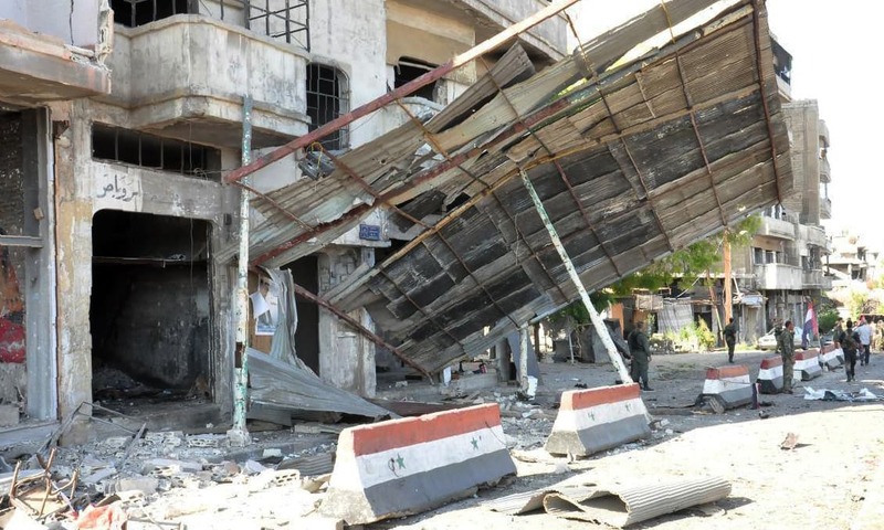 Syrian army soldiers inspecting the damage at the site of a suspected car bombing in a government-held area in the city of Homs. —AFP