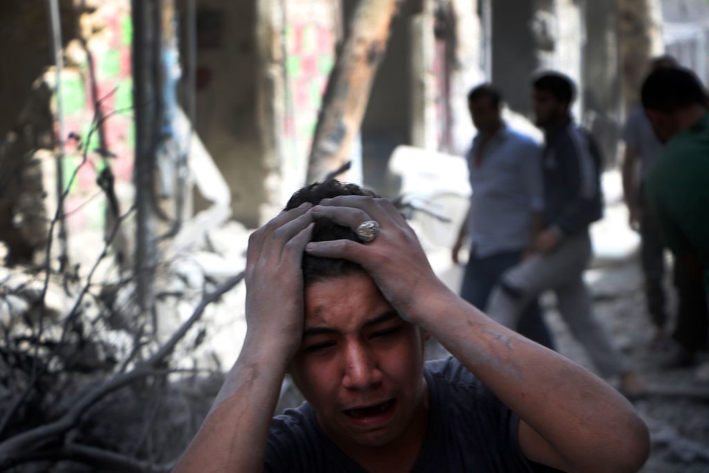 Syrian civilians are seen in the aftermath of renewed attacks on an opposition-controlled area in Aleppo on Tuesday