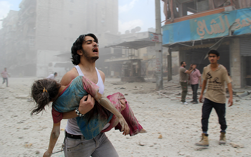 A man carries a young girl who was injured in a reported barrel-bomb attack by government forces in the northern city of Aleppo