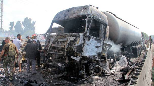 Syrian security forces emergency services and residents look at the remains of vehicles at the site of a bombing in Tartus