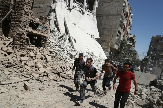 Syrians run for cover during reported government air strikes in the rebel-held town of Douma east of the capital Damascus