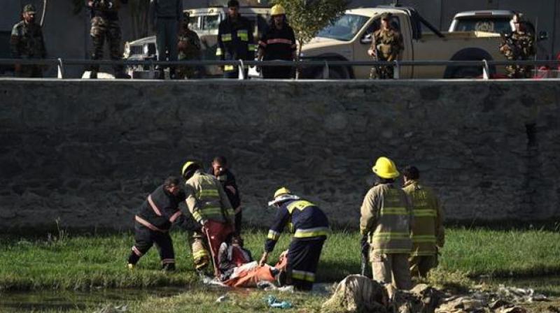 Afghan security personnel and firemen recover a body from the scene of a twin suicide bombing near the Ministry of Defence in Kabul