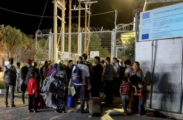 Refugees and migrants stand at the closed gate of the Moria migrant camp after a fire at the facility on the island of Lesbos Greece Sept. 19 2016