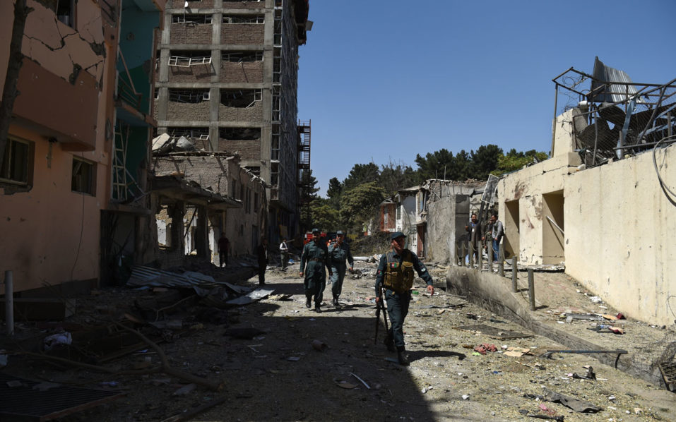 Afghan security personnel walk at the site following a car bomb blast that targeted the CARE International compound at Shar-e Naw in Kabul