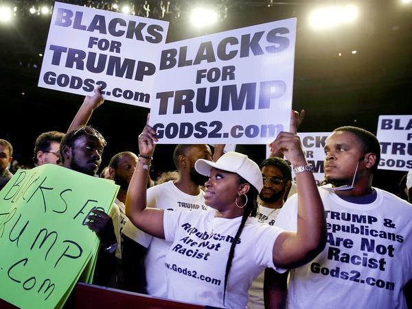 Supporters of Donald Trump hold signs at a campaign rally in Miami Florida on Friday