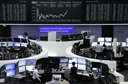 Traders work at their desks in front of the German share price index DAX board at the stock exchange in Frankfurt Germany