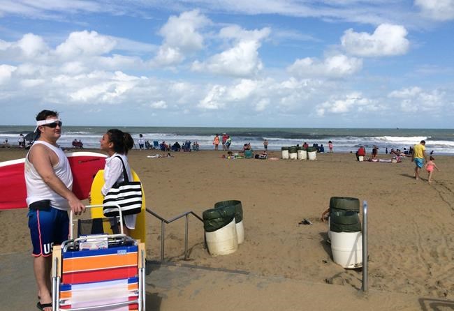 A man and a woman arrives at the Virginia Beach boardwalk in Virginia Beach Va. Sunday Sept. 4 2016. Hermine spun away from the East Coast on Sunday removing the threat of heavy rain but maintaining enough power to whip up dangerous waves and rip cur